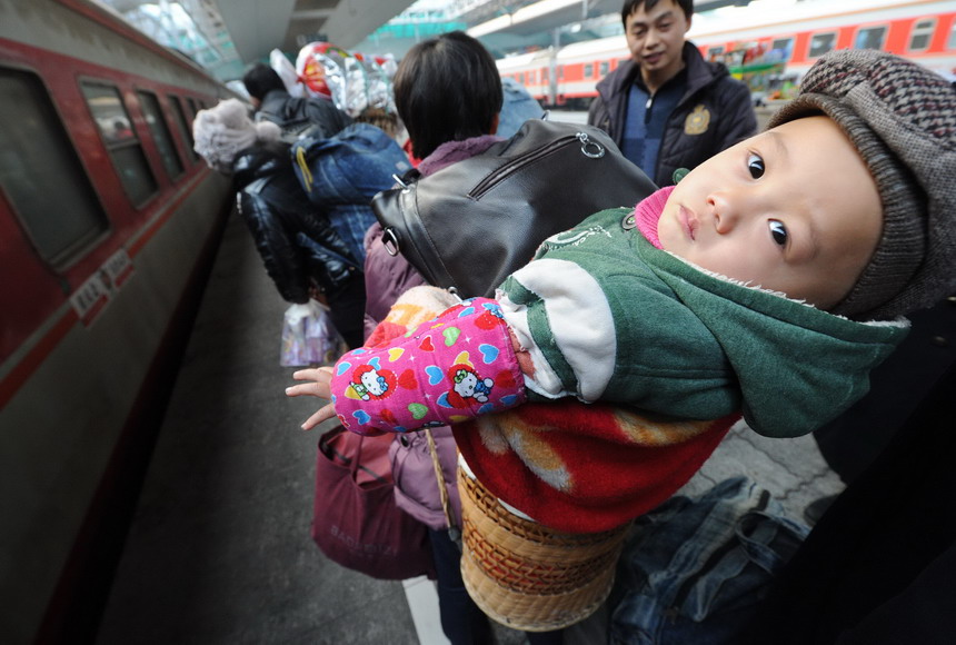 A kid in a basket on his grandmother’s back is about to get on a train heading to Urumqi on Jan. 23, 2013.  (Photo/Xinhua) 