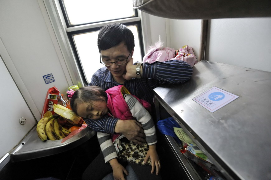 A girl falls asleep in the arms of her father in a narrow corner surrounded by washing basin and dust bin aboard a train heading to Chongqing, the destination of their standing journey on the train on Jan. 17, 2013. (Photo/Xinhua)