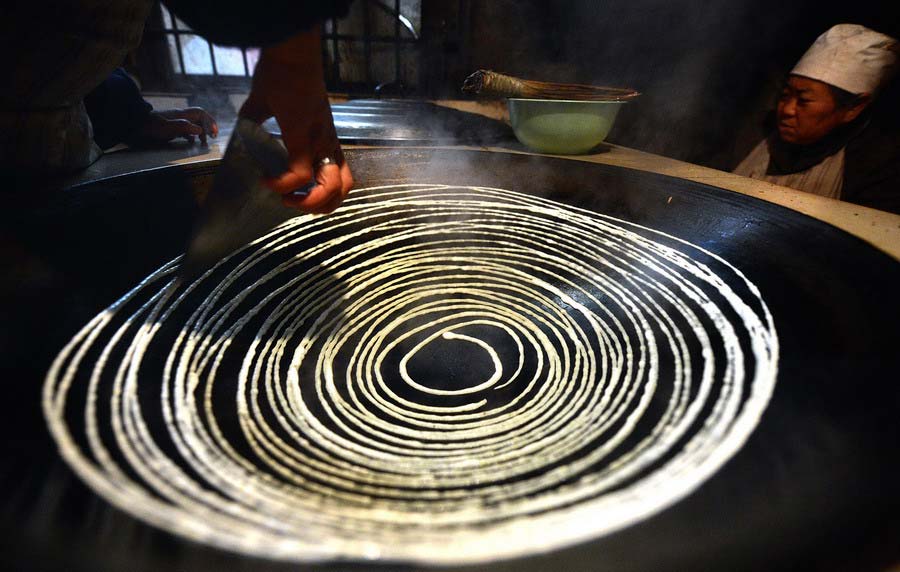 A resident of Miao nationality makes beancurd sheet, a tradition food in China to eat in the Spring Festival, in Miao Autonomous Prefecture of Hubei Province. (Photo/Xinhua)