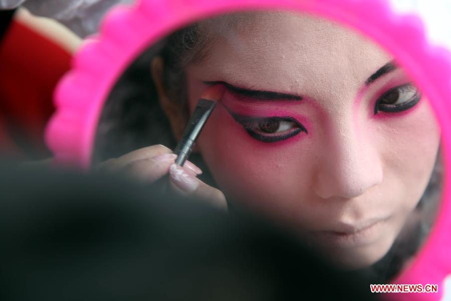 Wang Yijun, a learner of Puxian opera, one of the oldest forms of Chinese opera, makes up for performance at the Dongqin Village in Putian City, southeast China's Fujian Province, Jan. 26, 2013. Puxian opera, which originated from puppet shows, has been listed as a national intangible cultural heritage. (Xinhua/Lin Jianbing) 