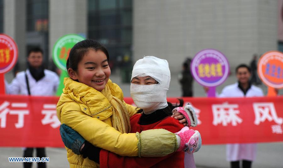 A passerby hugs with a a staff member dressed like a leprosy patient with bandage on the square of the Hefei Railway Station in Hefei, capital of east China's Anhui Province, Jan. 27, 2013. Staff members from a local center for disease control and prevention carried out a campaign to promote leprosy prevention here on Sunday, the 60th World Leprosy Day. (Xinhua/Liu Junxi)