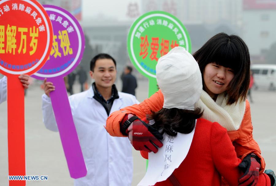 A passerby hugs with a staff member dressed like a leprosy patient with bandage on the square of the Hefei Railway Station in Hefei, capital of east China's Anhui Province, Jan. 27, 2013. Staff members from a local center for disease control and prevention carried out a campaign to promote leprosy prevention here on Sunday, the 60th World Leprosy Day. (Xinhua/Liu Junxi) 
