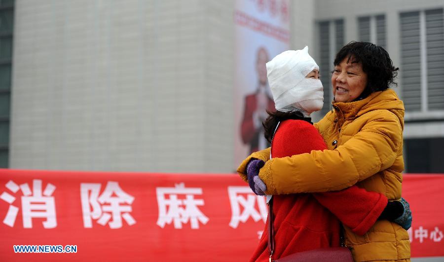 A passerby hugs with a a staff member dressed like a leprosy patient with bandage on the square of the Hefei Railway Station in Hefei, capital of east China's Anhui Province, Jan. 27, 2013. Staff members from a local center for disease control and prevention carried out a campaign to promote leprosy prevention here on Sunday, the 60th World Leprosy Day. (Xinhua/Liu Junxi)