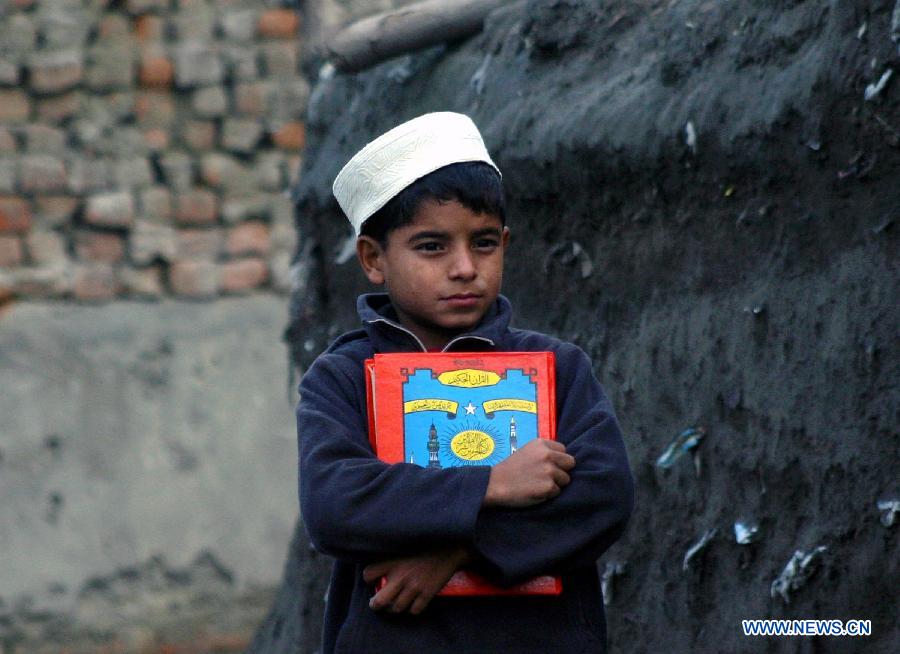 A boy holds holy Quran as he returns home after attending religious class in northwest Pakistan's Peshawar on Jan. 27, 2013. (Xinhua/Ahmad Sidique)