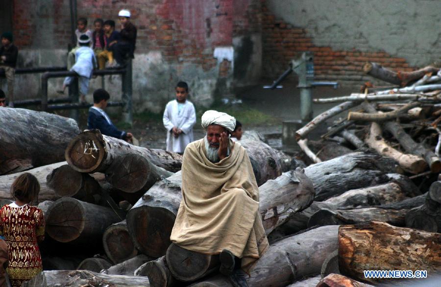 An old man sits on wood to be used as fuel for cooking and heating in northwest Pakistan's Peshawar on Jan. 27, 2013. (Xinhua/Ahmad Sidique)