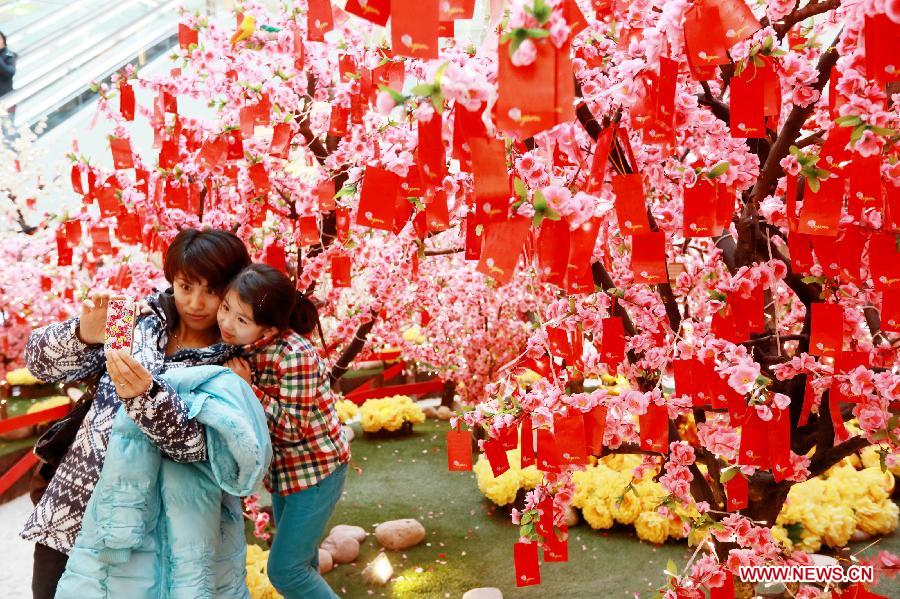 Visitors pose for photos with the wishing trees at a shopping mall in Wangfujing, a commercial area in Beijing, capital of China, Jan. 26, 2013. (Xinhua/Luo Wei)