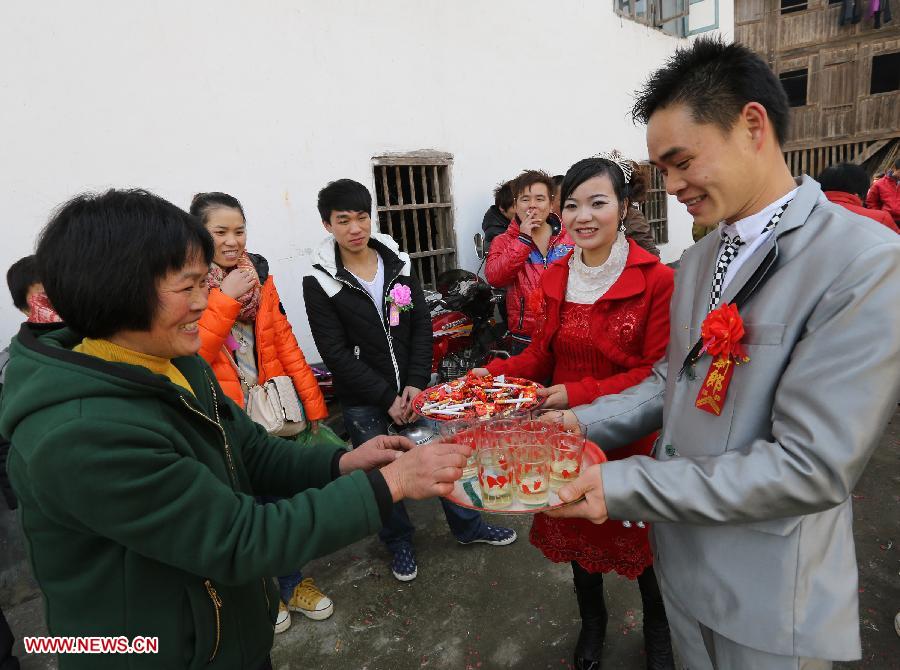 Groom Liang Fenghuang and bride Wei Lishan serve tea during their wedding ceremony at Chanru Village of Wangdong Town in Rongshui County, south China's Guangxi Zhuang Autonomous Region, Jan. 27, 2013. (Xinhua/Long Tao)
