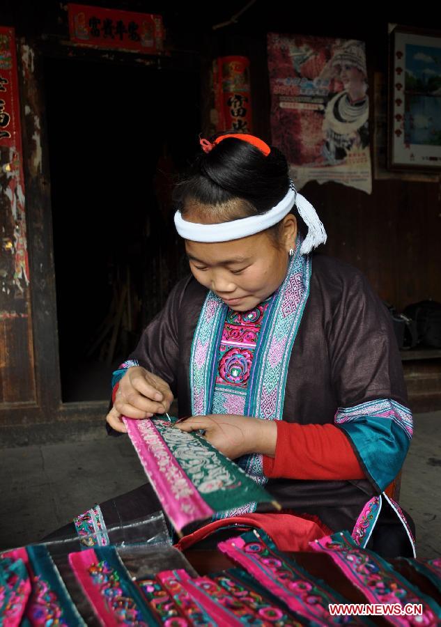 A woman of Dong ethnic group makes embroidery works at Tongle Village in Sanjiang Dong Autonomous County, southwest China's Guangxi Zhuang Autonomous Region, Jan. 26, 2013. The embroidery works made by Dong women have been sold to Britain. (Xinhua/Yang Ming)