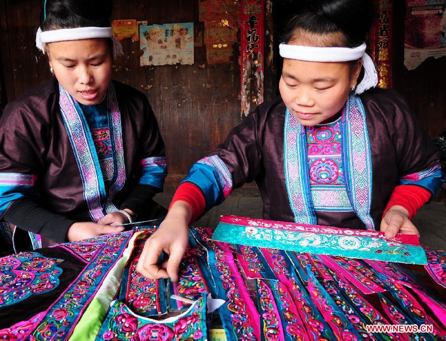 Women of Dong ethnic group make embroidery works at Tongle Village in Sanjiang Dong Autonomous County, southwest China's Guangxi Zhuang Autonomous Region, Jan. 26, 2013. The embroidery works made by Dong women have been sold to Britain. (Xinhua/Liang Kechuan)