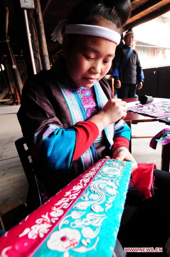 A woman of Dong ethnic group makes embroidery works at Tongle Village in Sanjiang Dong Autonomous County, southwest China's Guangxi Zhuang Autonomous Region, Jan. 26, 2013. The embroidery works made by Dong women have been sold to Britain. (Xinhua/Liang Kechuan)