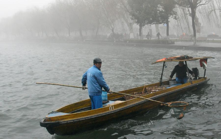 Sanitation workers clear off wastes drifting on the West Lake amid heavy fog in Hangzhou, capital of east China's Zhejiang Province, Jan. 28, 2013. The provincial meteorological observatory has issued an orange-coded alert on Jan. 28 morning as foggy weather here cut visibility to less than 500 meters and worsened air pollution in many cities. (Xinhua/Yue Deliang) 