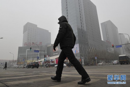 A pedestrian is seen walking through fog in Shijingshan district, Beijing, Jan. 23. Beijing's meteorological center on Monday issued a yellow-coded alert for haze as the fourth foggy weather in this month hit the city and cuts the visibility below 3,000 meters in major parts of Beijing. (Photo/Xinhua)