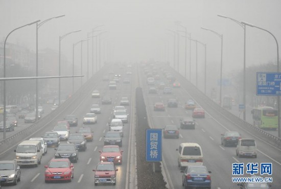 Vehicles run slowly on the fog enveloped East Third Ring Road of Beijing, Jan. 23. Beijing's meteorological center on Monday issued a yellow-coded alert for haze as the fourth foggy weather in this month hit the city and cuts the visibility below 3,000 meters in major parts of Beijing. (Photo/Xinhua)