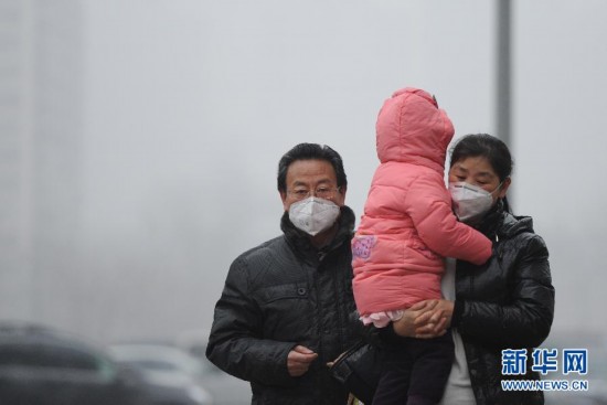 Mask-wearing Beijing residents walk in the street of the East Third Ring Road, Jan. 23. Beijing's meteorological center on Monday issued a yellow-coded alert for haze as the fourth foggy weather in this month hit the city and cuts the visibility below 3,000 meters in major parts of Beijing. (Photo/Xinhua)