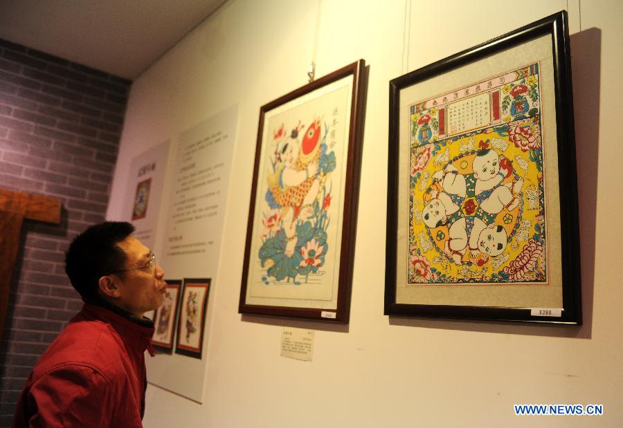 A visitor looks at paintings presented during an exhibition of traditional culture in Shijiazhuang, capital of north China's Hebei Province, Jan. 28, 2013. An 8-day exhibition in celebration of the coming Spring Festival was held in Shijiazhuang on Monday. (Xinhua/Zhu Xudong)