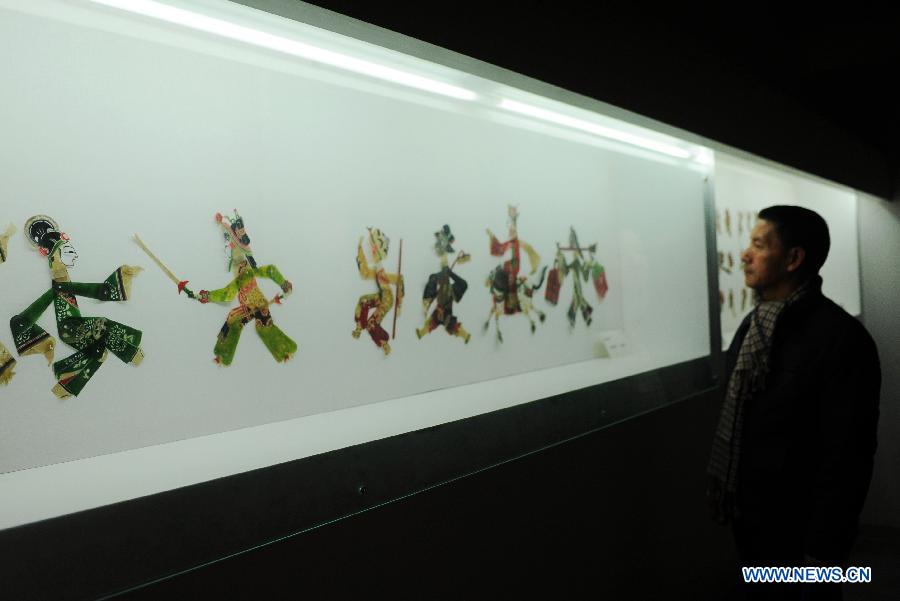 A visitor looks at the figures of Tangshan shadow play during an exhibition of traditional culture in Shijiazhuang, capital of north China's Hebei Province, Jan. 28, 2013. An 8-day exhibition in celebration of the coming Spring Festival was held in Shijiazhuang on Monday. (Xinhua/Zhu Xudong)