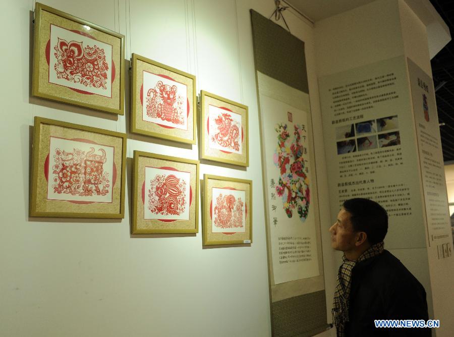 A visitor looks at paper-cut artworks during an exhibition of traditional culture in Shijiazhuang, capital of north China's Hebei Province, Jan. 28, 2013. An 8-day exhibition in celebration of the coming Spring Festival was held in Shijiazhuang on Monday. (Xinhua/Zhu Xudong)