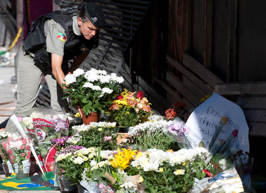A policeman puts flowers in front of the fire site of "Kiss" nightclub in Santa Maria, Brazil, on Jan. 28, 2013. So far, the fire's death toll is 231. (Xinhua/Weng Xinyang) 