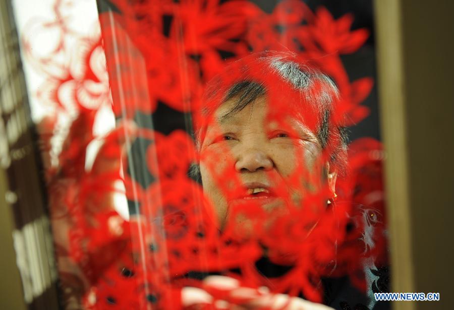 Liu Lanfang attaches a piece of paper cutting work to the window of her home in Shenmu County of northwest China's Shaanxi Province, Jan. 28, 2013. People began to make paper cuttings for the decoration of the upcoming Spring Festival here in recent days. (Xinhua/Li Yibo)