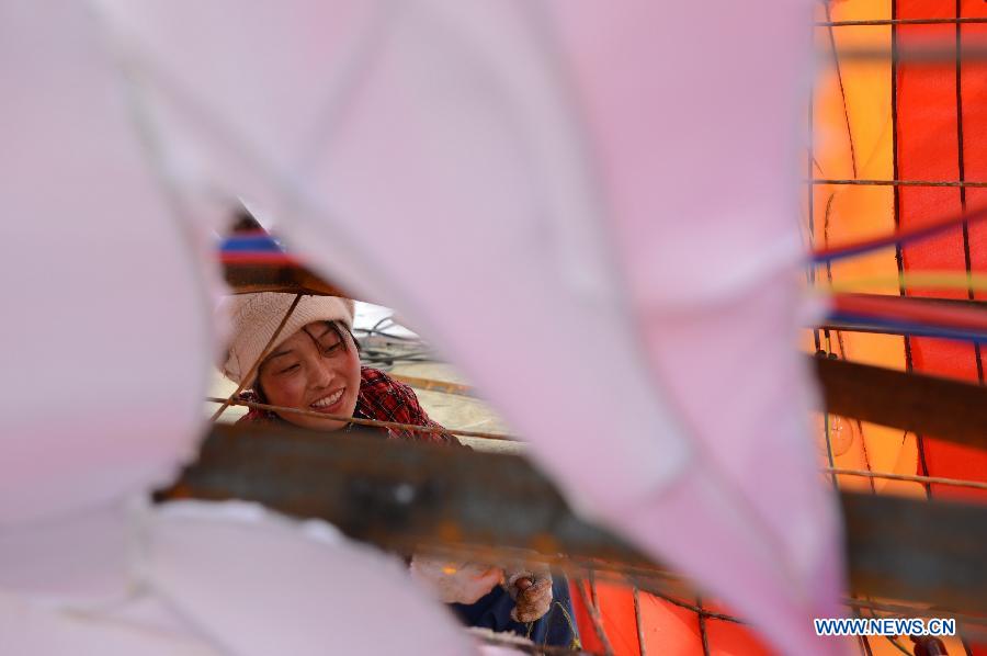 A woman works on a lantern on the street in Nanchang, capital of east China's Jiangxi Province, Jan. 28, 2013. Lanterns designed in Zigong of southwest China's Sichuan Province will meet with the residents here during the upcoming Spring Festival holiday. (Xinhua/Zhou Mi)