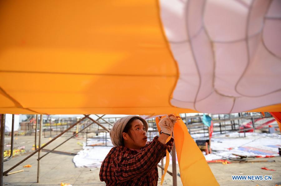 A woman works on a lantern on the street in Nanchang, capital of east China's Jiangxi Province, Jan. 28, 2013. Lanterns designed in Zigong of southwest China's Sichuan Province will meet with the residents here during the upcoming Spring Festival holiday. (Xinhua/Zhou Mi)