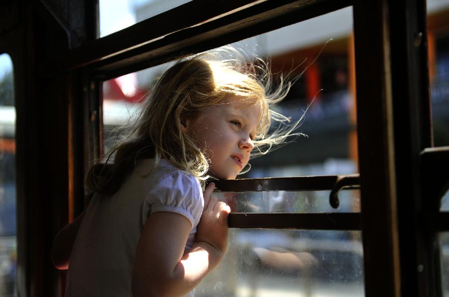 A girl looks out from the window of a tram in Melbourne, Australia, Jan. 28, 2013. Melbourne's trams network is one of the largest functioning tram networks in the world. Among all the routes, No. 35, the City Circle Tram provides a free and convenient way for visitors to see the sights of central Melbourne while experiencing a ride on one of the city's much loved heritage trams. (Xinhua/Chen Xiaowei)