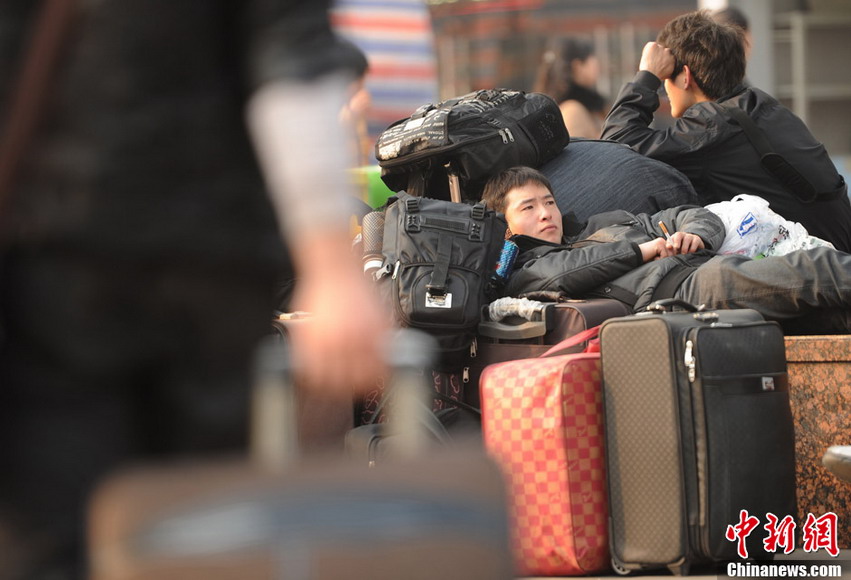 A traveler lies on bags to wait the train heading to home at a railway station (CNS/Chen Chao)