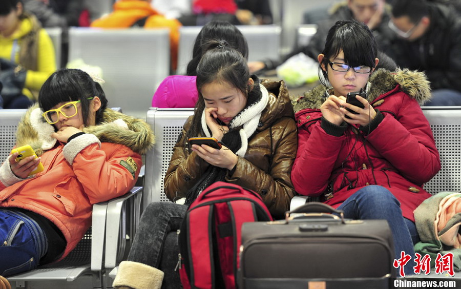 Mobile lovers: Girls play mobiles in the waiting hall on Jan. 26, 2013. (CNS/ Zhang Yong)