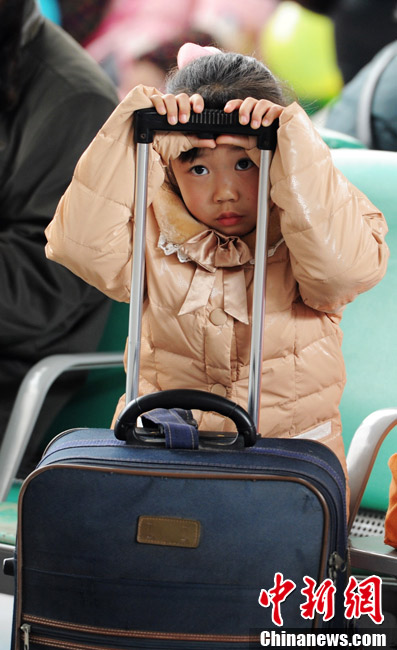 A little traveler holds handle bar of luggage to wait the train at Shangsha South Railway Station on Jan. 26, 2013. (CNS/Yang Huafeng)