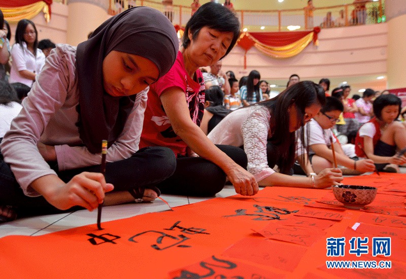 Each contestant writes down the Chinese character "she", meaning snake, on the piece of red paper with writing brush. The calligraphy works composed a 70-meters-long red scroll. (Xinhua Photo by Zhang Wenzong)