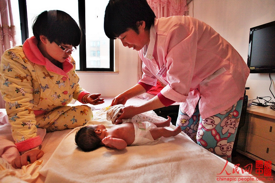 Zhang teaches the mother how to dress the baby.
