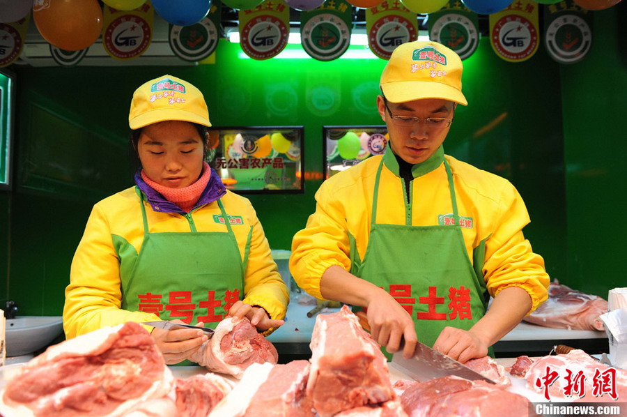 Hao Chengbin (R), a graduate from Jiangxi University of Finance and Economics, and Sun Xia (L), a graduate from University of Hainan, work at a "No.1 Pork" butcher shop in Shanghai on Jan. 29, 2013.(Photo/CNS) 