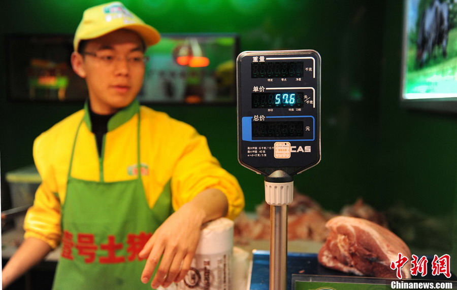 Hao Chengbin (R), a graduate from Jiangxi University of Finance and Economics, weights the pork for a buyer at a "No.1 Pork" butcher shop in Shanghai on Jan. 29, 2013. (Photo/CNS)