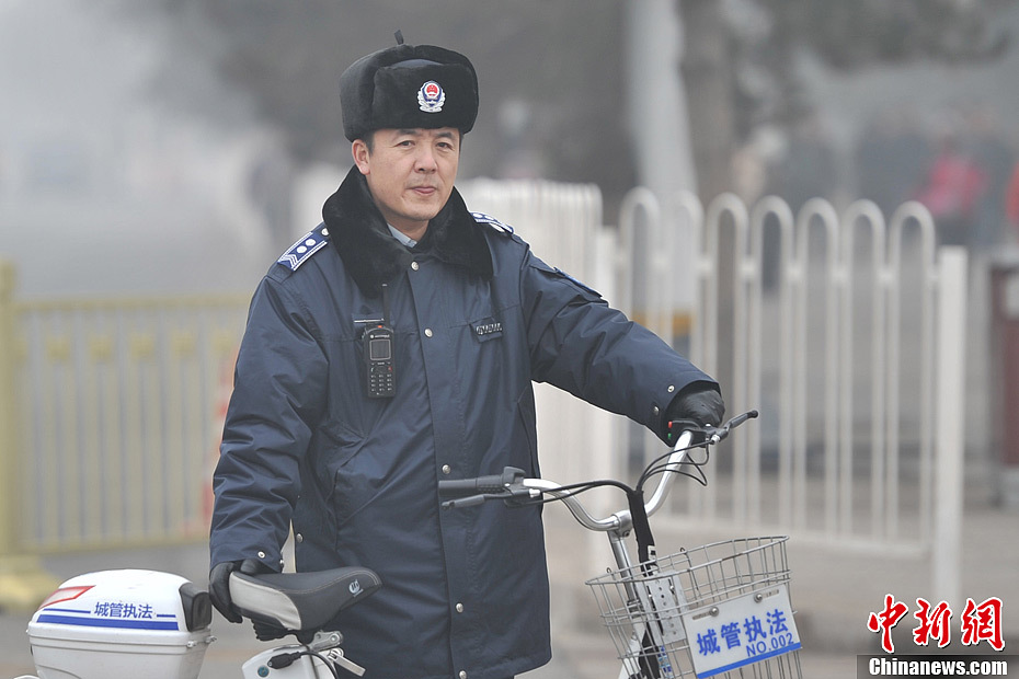 A photo taken on Jan. 29 shows an urban management official standing in the smog-shrouded street. The fourth round of heavy smog in four weeks hit Beijing on Tuesday and led to serious air pollution, which has sent more people with respiratory illnesses to hospitals. However, a group of people had to stay on jobs outdoors. (Chinanews.com/Jin Shuo)