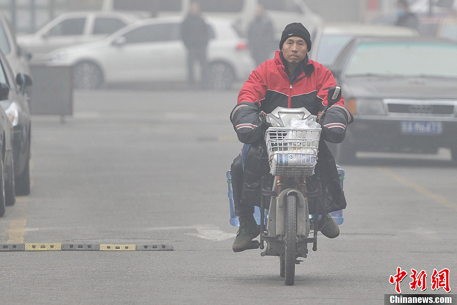A photo taken on Jan. 29 shows a bottled water deliveryman working in the foggy weather. The fourth round of heavy smog in four weeks hit Beijing on Tuesday and led to serious air pollution, which has sent more people with respiratory illnesses to hospitals. However, a group of people had to stay on jobs outdoors. (Chinanews.com/Jin Shuo)