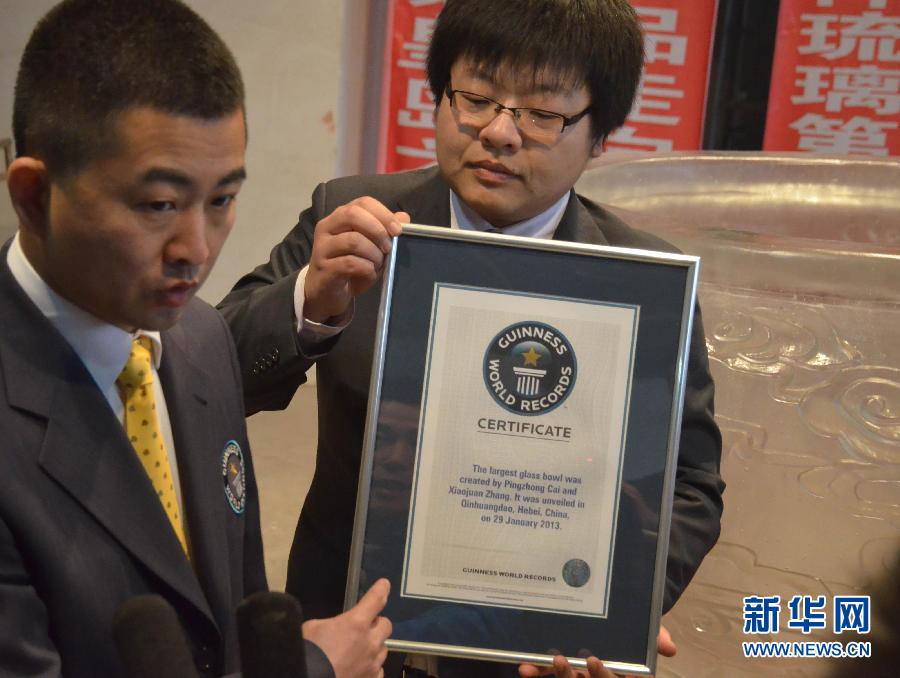 An officer (L) from the headquarters of Guinness World Records in Britain announce the authentication result for the largest glass bowl in the world on Jan. 29, 2013.(Xinhua/Cui Lisheng)