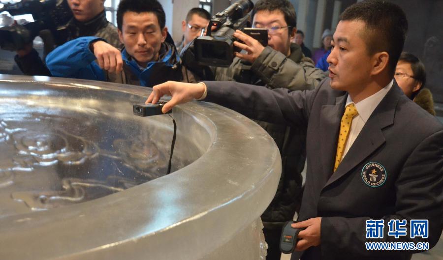 An officer from the headquarters of Guinness World Records measures the glass bowl before announcing it to be the largest glass bowl in the world on Jan. 29, 2013. (Xinhua/Cui Lisheng)