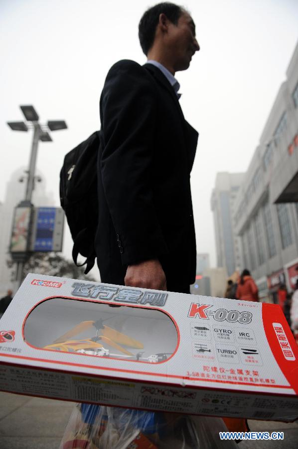 A passenger holding a gift for his nephew enters the Zhengzhou Railway Station in Zhengzhou, capital of central China's Henan Province, Jan. 30, 2013. The 40-day Spring Festival travel rush started on Jan. 26. The Spring Festival, which falls on Feb. 10 this year, is traditionally the most important holiday of the Chinese people. It is a custom for families to reunite in the holiday, a factor that has led to massive seasonal travel rushes in recent years as more Chinese leave their hometowns to seek work elsewhere. Public transportation is expected to accommodate about 3.41 billion travelers nationwide during the holiday, including 225 million railway passengers.(Xinhua/Li Bo) 