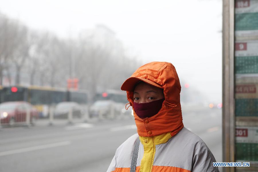 A woman with mask waits at a bus stop in Beijing, capital of China, Jan. 30, 2013. The meteorological observatory in Beijing issued an orange alert and a yellow alert against heavy fog and haze respectively on 6:00 am Wednesday. Heavy fog has been lingering in central and eastern China since Tuesday afternoon, disturbing the traffic. (Xinhua/Li Fangyu) 