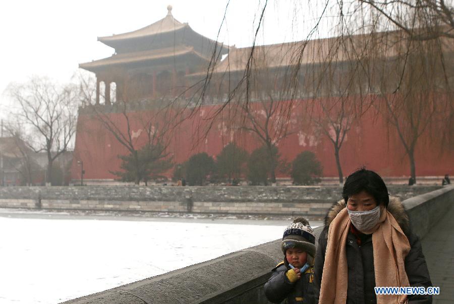 Pedestrians with masks walk past the moat of the Forbidden City in Beijing, capital of China, Jan. 30, 2013. The meteorological observatory in Beijing issued an orange alert and a yellow alert against heavy fog and haze respectively on 6:00 am Wednesday. Heavy fog has been lingering in central and eastern China since Tuesday afternoon, disturbing the traffic. (Xinhua/Li Fangyu) 