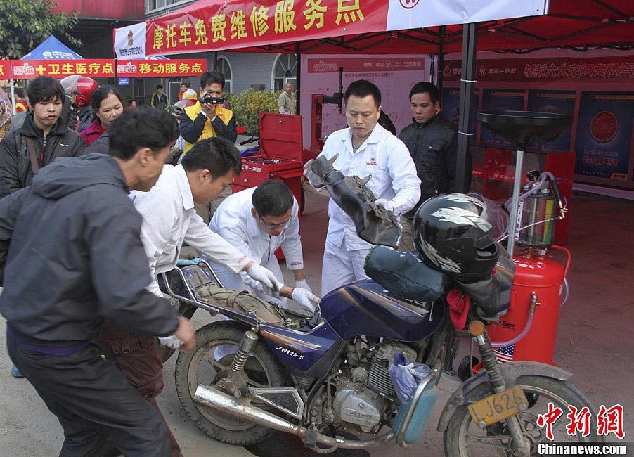 Volunteers fix a motorbike which takes a worker’s family home for free, Jan. 30. On Wednesday, about 5,000 motorbikes taking migrant workers home from Guangdong run into the neighboring Guangxi Zhuang Autonomous Region for the upcoming Spring Festival. Traffic police said about 3,000 such bikes passed through the county every day thanks to the well-developed roads connecting Guangxi and Guangdong. Local government offered free services including police escort, food, beverage and medical care to these homecoming people on the motorbike. (Photo/Chinanews.com)