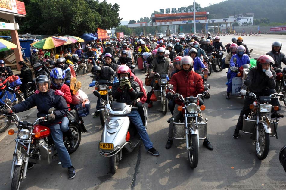 Migrant workers who are on the way home by motorbike take short rest at a highway toll station in Fengkai county, south China's Guangdong province, Jan. 30. On Wednesday, about 5,000 motorbikes taking migrant workers home from Guangdong run into the neighboring Guangxi Zhuang Autonomous Region for the upcoming Spring Festival. Traffic police said about 3,000 such bikes passed through the county every day thanks to the well-developed roads connecting Guangxi and Guangdong. Local government offered free services including police escort, food, beverage and medical care to these homecoming people on the motorbike. (Photo/Image China)