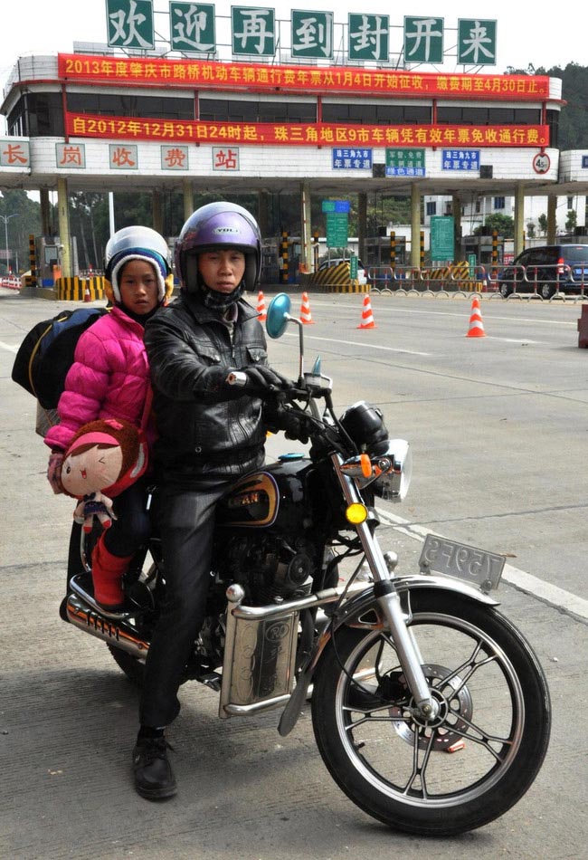 A migrant worker and daughter return home by motorbike after resting at a highway toll station in Fengkai county, south China's Guangdong province, Jan. 30. On Wednesday, about 5,000 motorbikes taking migrant workers home from Guangdong run into the neighboring Guangxi Zhuang Autonomous Region for the upcoming Spring Festival. Traffic police said about 3,000 such bikes passed through the county every day thanks to the well-developed roads connecting Guangxi and Guangdong. Local government offered free services including police escort, food, beverage and medical care to these homecoming people on the motorbike. (Photo/Image China)