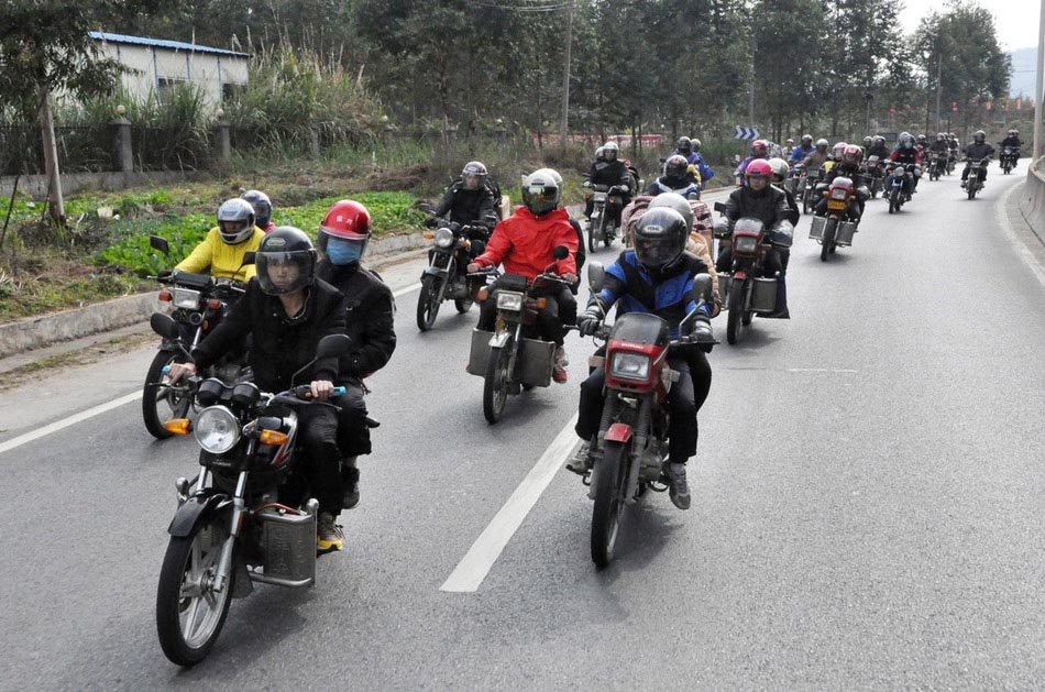 A team of migrant workers are on the way home by motorbike on 321 National Highway in Fengkai county, south China's Guangdong province, Jan. 30. On Wednesday, about 5,000 motorbikes taking migrant workers home from Guangdong run into the neighboring Guangxi Zhuang Autonomous Region for the upcoming Spring Festival. Traffic police said about 3,000 such bikes passed through the county every day thanks to the well-developed roads connecting Guangxi and Guangdong. Local government offered free services including police escort, food, beverage and medical care to these homecoming people on the motorbike. (Photo/Image China)