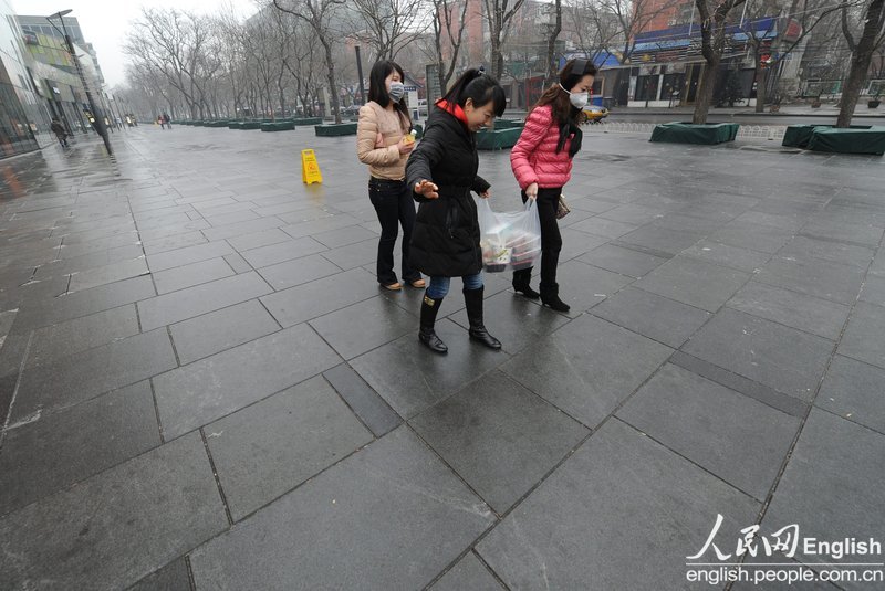 Rain and light snow falls in Beijing slightly disperse the lingering smog that suffocated the city for a few days. A fresh cold front hit the central and eastern China on Thursday and was expected to ease the smog that suffocated these areas in the past few days. Because of the freezing temperature, the rainwater turned to thin ice on the road, leading to many slips and traffic accidents in Beijing on Thursday. (Photo/CFP)