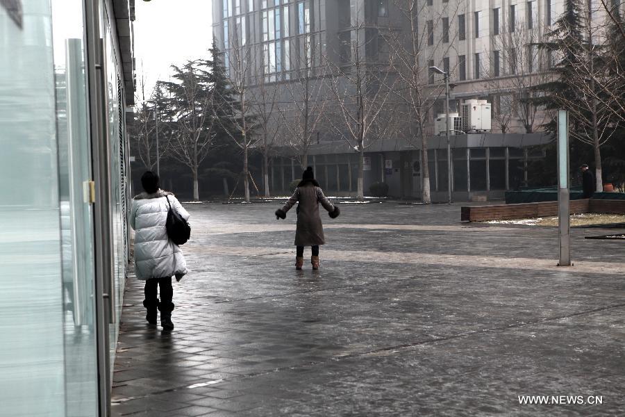 Two women walk on an icy square at the CBD of Beijing, capital of China, Jan. 31, 2013. Light snow hit parts of the city on Thursday and the local meteorological observatory issued a yellow alert for icy road. (Xinhua/Jin Liwang) 
