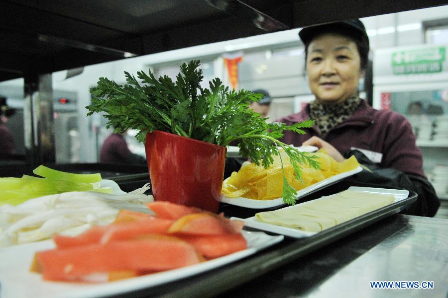 A working staff sides dishes in a half portion compared to the normal at a hot pot restaurant in Lanzhou, capital of northwest China's Gansu Province, Jan. 30, 2013. A "half portion, half price" activity was launched by numerous hot pot restaurant to advocate saving here Wednesday. (Xinhua/Chen Bin)