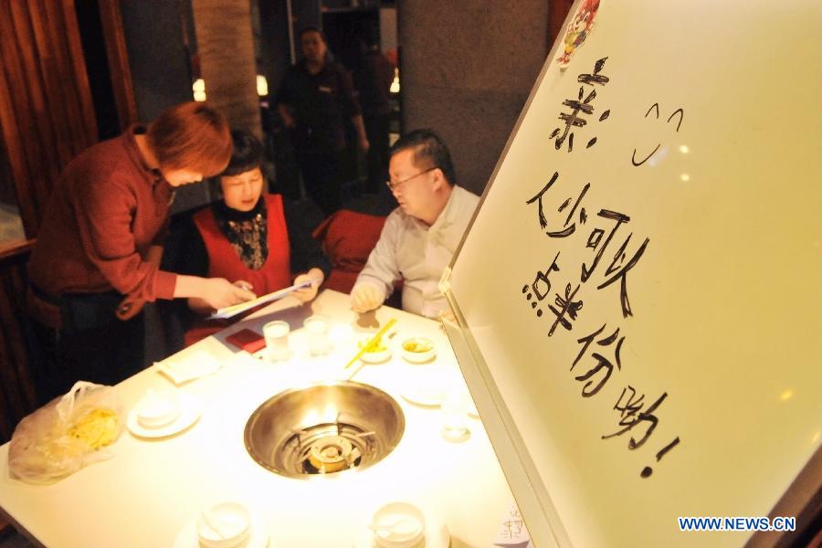 Customers order at a hot pot restaurant in Lanzhou, capital of northwest China's Gansu Province, Jan. 30, 2013. A "half portion, half price" activity was launched by numerous hot pot restaurant to advocate saving here Wednesday. (Xinhua/Chen Bin)