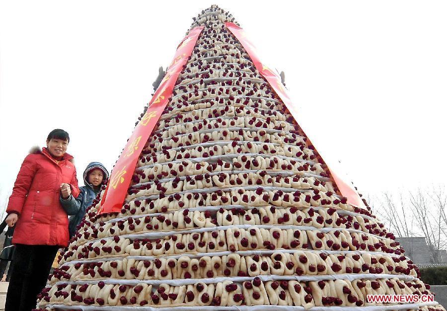 Citizens watch a hill of steamed jujube buns in a street in Xinzheng City, central China's Henan Province, Feb. 3, 2011. The steamed jujube bun is a traditional food usually eaten during the Spring Festival or Chinese Lunar New Year period in the central China region. Local people follows a custom to make steamed buns jujube on the 28th day of the first lunar month. Chinese people who live in the central China region have formed various traditions to celebrate the Chinese Lunar New Year. (Xinhua/Wang Song)