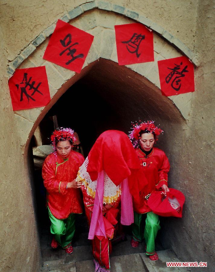 A bride (C) with a red cloth on the head walks along a corridor to her wedding ceremony in Zhangbian Township of Shanxian County, central China's Henan Province, Feb. 9, 2000. People who live in the central China region usually hold wedding ceremonies during the festive Spring Festival period. (Xinhua/Wang Song)